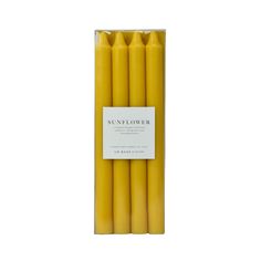 six yellow candles in a cardboard box on a white background with a label that says sunflower