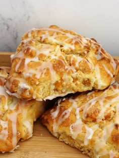 four glazed scones sitting on top of a wooden cutting board