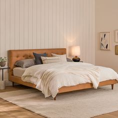 a large bed sitting on top of a wooden floor next to a white carpeted wall