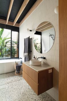 a bathroom with a sink, mirror and bathtub in front of a large window