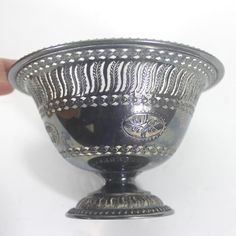 a silver bowl with designs on it being held by a hand