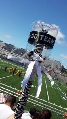 a football field with fans holding up an inflatable helmet that says go team