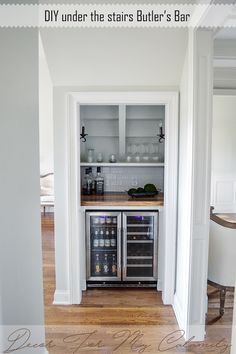 an open refrigerator in the corner of a kitchen with white walls and wood floors, along with a built - in wine cooler