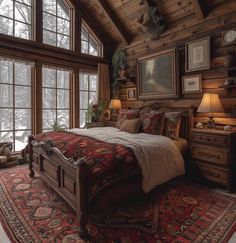 a large bed sitting in a bedroom on top of a red and white rug next to two windows