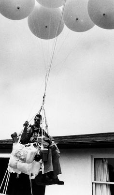 a man is holding onto some balloons in the air while another person holds on to them