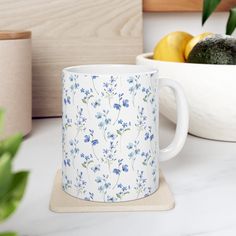 a blue and white mug sitting on top of a counter next to some lemons