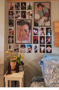 a bedroom with pictures on the wall and vases filled with flowers in front of it