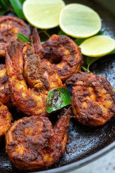 some fried food is in a frying pan with lemon slices and green leaves on the side