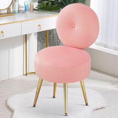 a pink chair sitting on top of a white rug in front of a desk with a mirror