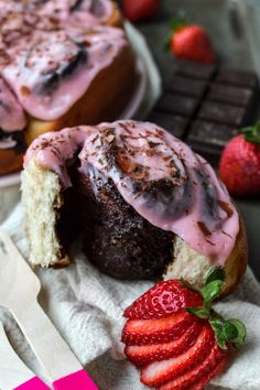 there is a chocolate bunt cake with pink icing and strawberries on the side