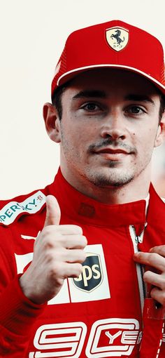 a man in a red racing suit giving the thumbs up