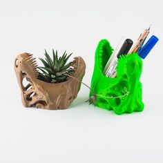 a green planter with pencils and pens in it next to a clay sculpture