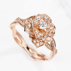 a rose shaped diamond ring on top of a white surface