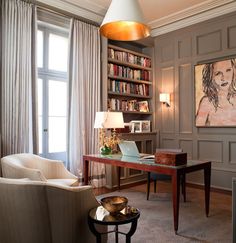 a living room filled with furniture and bookshelves next to a painting on the wall