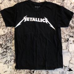 Metallica Graphic T Shirt Never Worn Casual White Top With Band Logo, Black Band Logo Shirt For Summer, Black Shirt With Band Logo For Summer, White Casual Top With Band Logo, Black Fan Merchandise Shirt For Summer, Black Summer Shirt With Band Logo, Casual Short Sleeve Shirt With Band Logo, Black Spring Fan Merchandise Tops, Band Logo Tops For Spring Streetwear