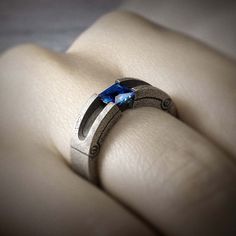 a close up of a ring on a person's hand with a blue stone