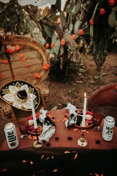 an outdoor table with candles and other items on it in front of cacti