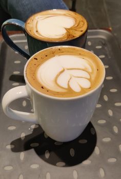 two cups of coffee sitting on top of a metal tray