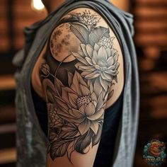 a woman's arm with flowers on it and the moon in the sky behind her