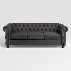 a black couch with studding on the arm and backrests, sitting against a white background