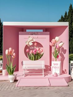 a white bench sitting in front of a pink building with flowers on the side and a sign next to it