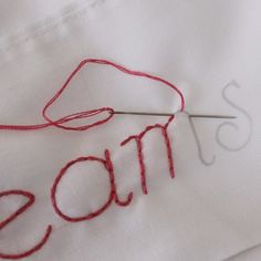 a close up of a piece of cloth with the word mom on it and knitting needles