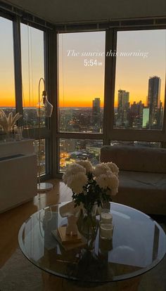 a living room filled with furniture and a large window overlooking the city at sunset or dawn