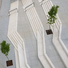 an aerial view of some concrete structures with trees in the center and two benches on each side