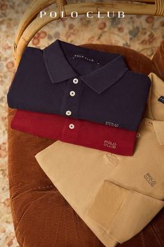 three polo shirts sitting on top of a chair