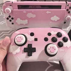 a person is holding a pink controller for a video game system that looks like it has paw prints on it