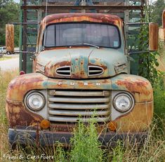 an old rusty truck sitting in the grass