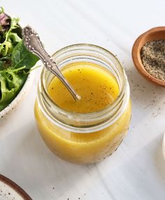 a glass jar filled with liquid next to a salad