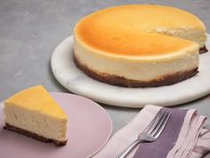 a cheesecake sitting on top of a white plate next to a slice of cake