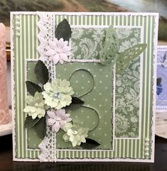 a close up of a card on a table with flowers and lace around the edges