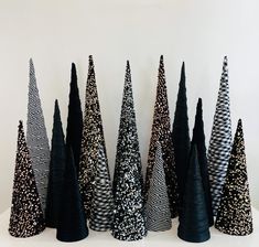 black and white christmas trees are lined up on a table with silver glittered cones