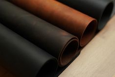 four rolls of leather sitting on top of a wooden table