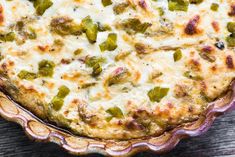 a casserole with cheese and green peppers in a pie dish on a wooden table