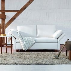 a white couch sitting on top of a rug next to a table