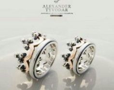 two white and gold wedding rings with black diamonds on them, set against a white background