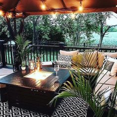 an outdoor living area with couches, tables and lights on the patio roof over looking water