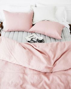 a bed with pink sheets and pillows on it