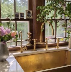 a kitchen sink sitting under a window next to a vase with flowers