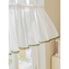 a kitchen window curtain with green trim and pom - poms on the edge