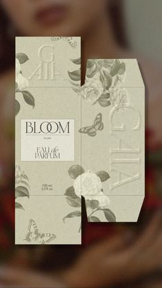 a close up of a person holding a box with flowers on it and the words bloom written in white