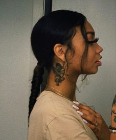 a woman with a tattoo on her neck looking into the distance while standing in front of a mirror