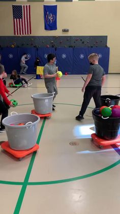 children playing with buckets and tennis balls in an indoor gym