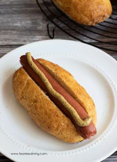 a hot dog on a bun sitting on a plate next to a loaf of bread