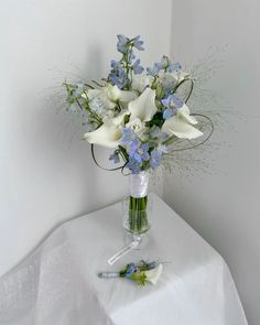 a vase filled with white and blue flowers on top of a table next to a pen