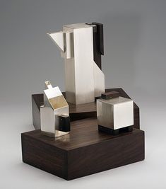 an abstract sculpture is displayed on a wooden stand with white cubes and black squares