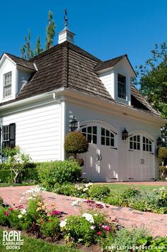 a white house with flowers in the front yard